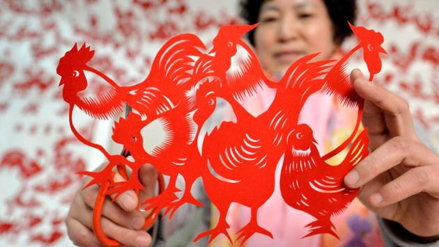A folk craftswoman Feng Shiping shows a paper cutting of a rooster she made for the upcoming Chinese New Year in Handan, north China's Hebei province. (AFP)