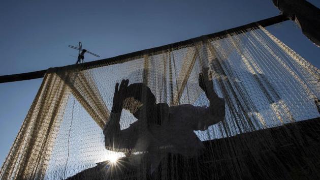 This photo taken on November 23, 2016 shows a fisherman cleaning his net near the Irrawaddy river in Mandalay. Loved for generations for corralling the catch into fishermen's nets, the 'smiling' Irrawaddy dolphins are being killed in record numbers by rogue gangs who use car batteries to stun aquatic life. The illegal technique now threatens to wipe out the dolphins and the tourist bonanza they promise. (Ye Aung Thu/AFP)