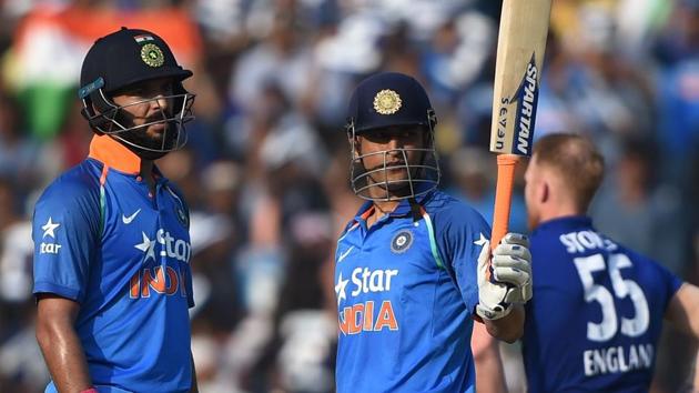 Mahendra Singh Dhoni raises his bat after completing his half century as Yuvraj Singh looks on during the second One Day International between India and England at the Barabati Stadium in Cuttack on Thursday.(AFP)