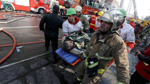 Firefighters carry a wounded comrade as they battle a blaze that engulfed Iran's oldest high-rise building. (AFP) Firefighters carry a wounded comrade as they battle a blaze that engulfed Iran's oldest high-rise building. (AFP)
