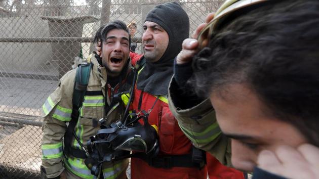 A firefighter consoles his comrade after the collapse of Iran's oldest high-rise. (AFP) A firefighter consoles his comrade after the collapse of Iran's oldest high-rise. (AFP)