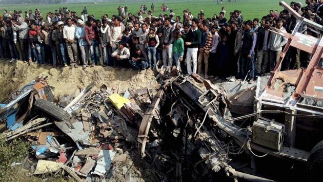 People looking at the mangled remains of vehicles after a school bus collided with a lorry amid dense fog on Aliganj-Paliyali road in Etah district on Thursday.(PTI Photo)