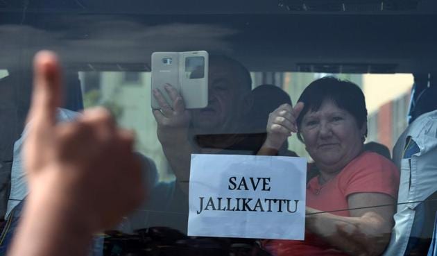 A foreign tourist raises her thumb and holds a placard against the car window as she passes students during a demonstration against the ban on the Jallikattu bull taming ritual and a call for a ban on animal rights orgnisation PETA, in Chennai on January 21.(AFP)