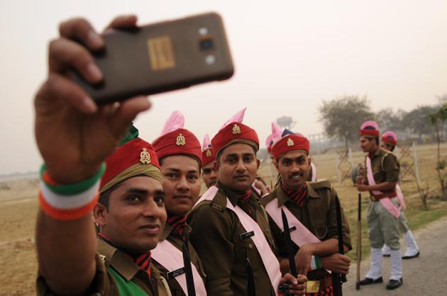 Uttar Pradesh Armed Police personnel click a selfie before taking part in the parade. (Burhaan Kinu/HT PHOTO)