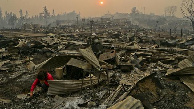 Constanza Vega searches the charred remains of her home for coins she had saved up, after a fire in Santa Olga, Chile. (Esteban Felix/AP) Constanza Vega searches the charred remains of her home for coins she had saved up, after a fire in Santa Olga, Chile. (Esteban Felix/AP)
