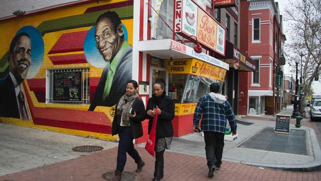 People walk past a mural of former US President Barack Obama and comedian Bill Cosby painted on the side of Ben's Chili Bowl in Washington, DC.(AFP File)
