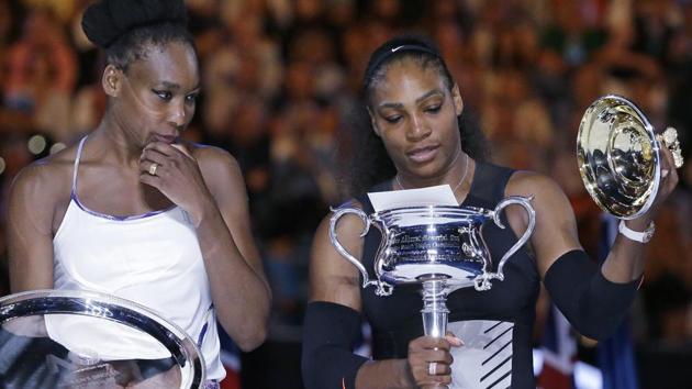 Serena Williams (right) takes the lid off her trophy as sister Venus watches. (AP)