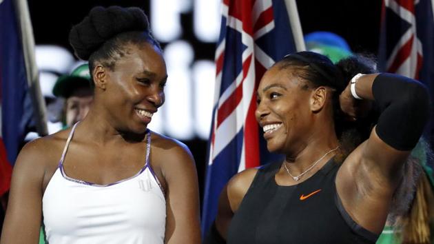 Serena Williams (right) and her sister Venus smile before the presentation ceremony of the Australian Open. (AP)