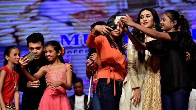 Karan Johar and Karisma Kapoor pose for selfies with children at the function. (Arijit Sen/HT PHOTO)