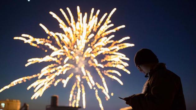 A man looks at his phone as fireworks explode on the eve of the Chinese Lunar New Year, or the Spring Festival, in Lianyungang, Jiangsu province, China. (REUTERS)