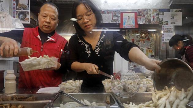 In this Monday, Jan. 23, 2017 photo, chicken feet snacks shop owner Leung Kin-kung, left, and his wife Leung pack chicken feet takeaway for customer in Hong Kong. Saturday marks the start of the lunar Year of the Rooster and families in China will reunite for festivities, fireworks and food. While tradition calls for feasting on “auspicious” foods, many will also munch on staple snacks like phoenix claws, the Chinese name for chicken feet. (Vincent Yu/AP)