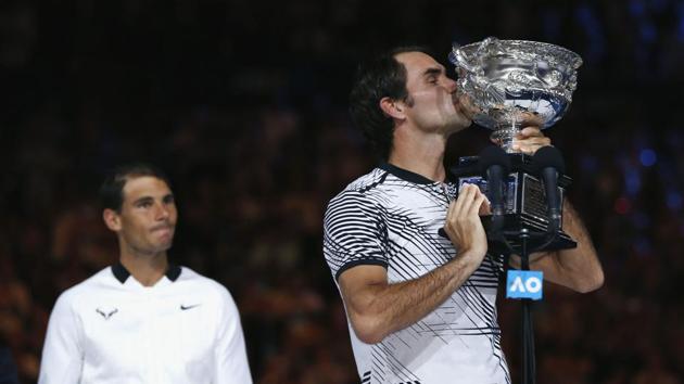 Roger Federer kisses the trophy as Rafael Nadal looks on. (REUTERS)