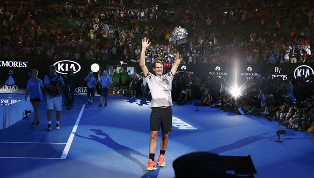 Roger Federer holds up the trophy for the crowd at Melbourne Park, on Sunday. (REUTERS)