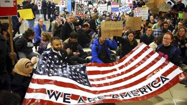 Protestors hold up an American flag at the airport.
