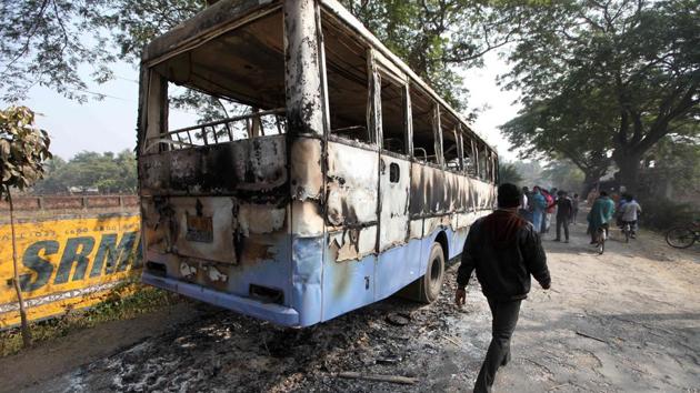 Local people walk past a burnt-out state transport bus in Bhangar, Kolkata.Two of the villagers protesting against an upcoming power substation were killed in alleged police firing at Bhangar, in South 24 Parganas district of West Bengal.(AFP Photo)