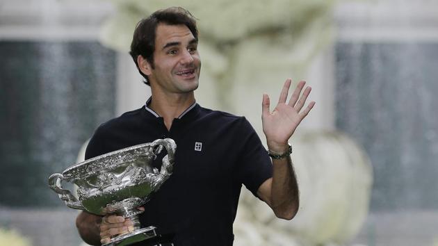 Roger Federer waves to fans as he holds his Australian Open trophy at Carlton Gardens in Melbourne on Monday.(AP)