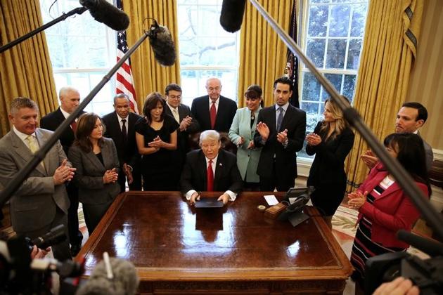 US President Donald Trump signs an executive order cutting regulations, accompanied by small business leaders at the Oval Office of the White House in Washington.(Reuters Photo)