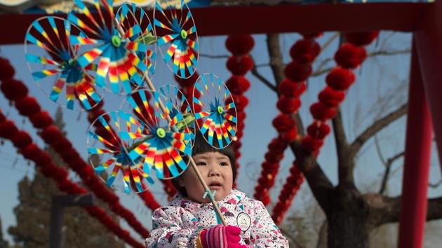 A little girl holds colourful pinwheels at a Spring Festival fair. The holidays are a time for families to get together and go out to fairs and restaurants. (Nicolas ASFOURI / AFP)