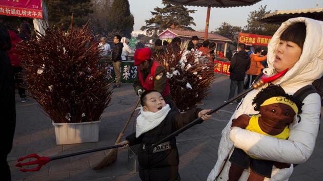 A child swings a toy weapon at a woman during a Spring Festival carnival in Beijing. A series of activities such as lion dancing, dragon lantern dancing, lantern festivals and temple fairs are held for the week. (Ng Han Guan / AP)