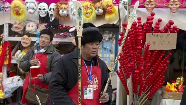 A vendor waits for customers to buy toy weapons at a Spring Festival carnival in Beijing. Shops and kiosks at the fairs do brisk business as people buy new clothes and gifts. (Ng Han Guan / AP)