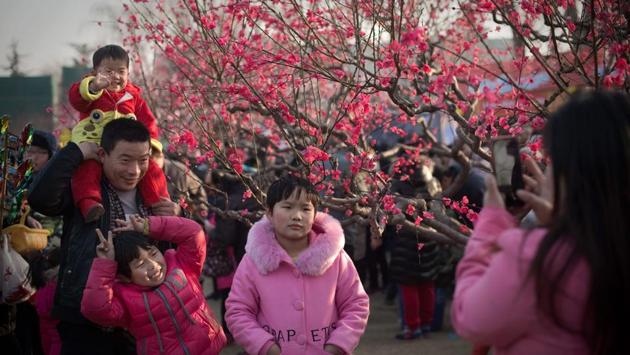 People pose for a photo in a park next to a real tree decorated with fake plastic flowers at a Spring Festival fair in Beijing. The festival usually falls on the first day of the lunar month, one month after the Gregorian calendar. (Nicolas ASFOURI / AFP)