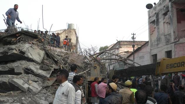 Residents stand near the debris of the under-construction building which collapsed in Kanpur on Wednesday.(AFP)
