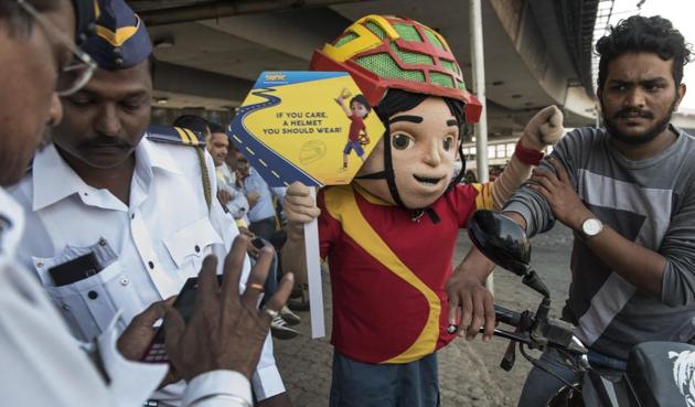 Traffic policemen, accompanied by a mascot of Shiva — a superhero from an animated TV show — catch a biker for not wearing a helmet, at Bandra on Tuesday.(Satish Bate/HT)