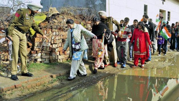 Patiala MLA Preneet Kaur walks cautiously at a waterlooged road during an election campaign for her husband Capt Amrinder Singh in Patiala. (PTI)