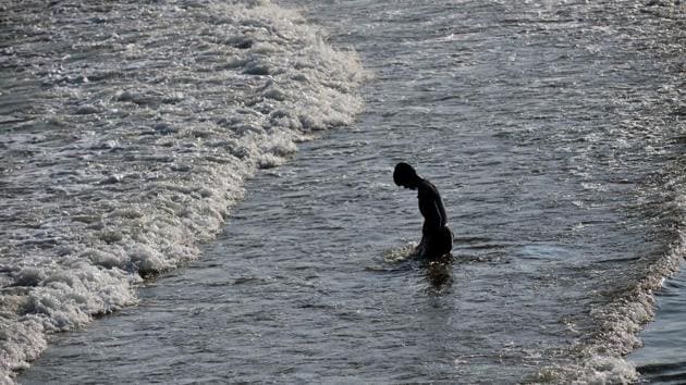A member of the Pollution Response Team collects a sample of the oil spill from boulders at the coast. 