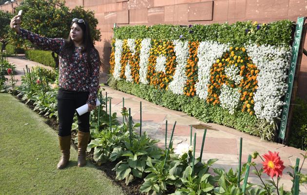 A visitor click selfie with flower decorated plaque at Mugha Gardens. The garden will be open for visitors till March. (Sonu Mehta/HT PHOTO) 