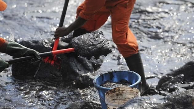 Members of Pollution Response Team of the Indian Coast Guard tackle the oil spill from boulders at the Ennore coast, in Chennai. 