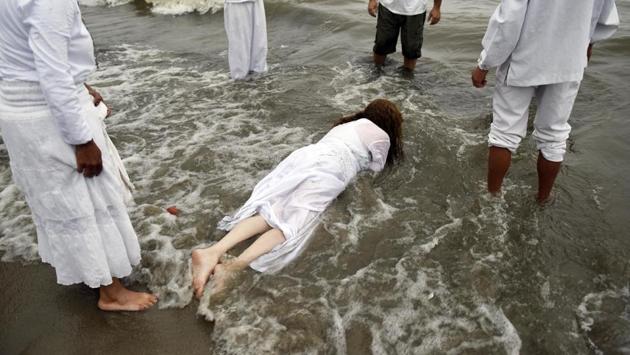 A woman lies face down in the water during a ritual honoring the African sea goddess Yemanja, in Montevideo, Uruguay, Thursday, Feb. 2, 2017. (Matilde Campodonico / AP)