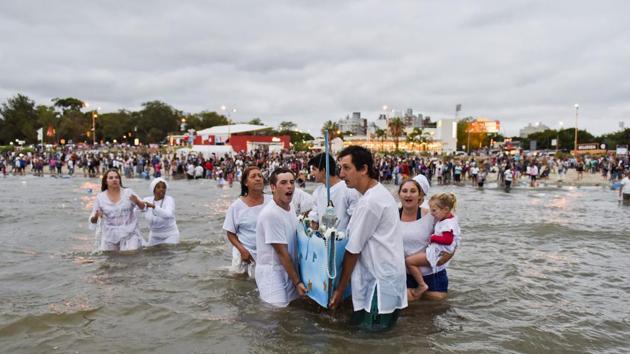 Worshippers enter ocean waters singing and leading a boat with offerings for the African sea goddess Yemanja, in Montevideo, Uruguay, Thursday, Feb. 2, 2017. (Matilde Campodonico/ AP)