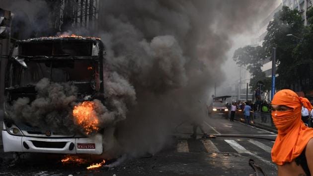 Civil servants protesting against austerity measures clash with riot police and set fire to a bus on Rio Branco, the main avenue in Rio de Janeiro, Brazil, while firefighters attempt to put out the blaze. (VANDERLEI ALMEIDA / AFP)
