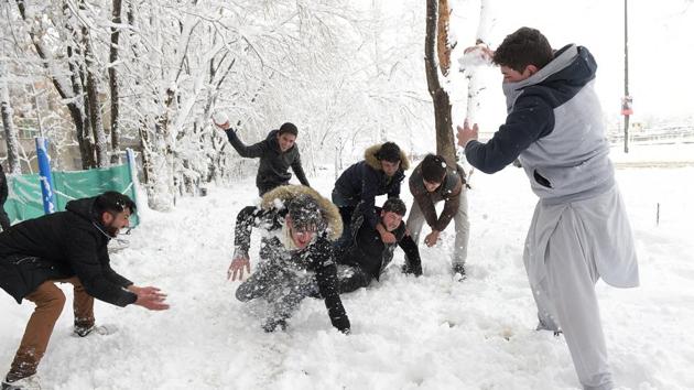 Afghan men play with snowballs in Kabul on Sunday. Avalanches and freezing weather have killed more than 100 people in different areas of Afghanistan, as rescuers worked to save scores still trapped under the snow.(AFP)