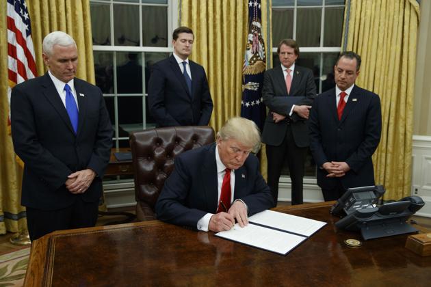 In this January 20, 2017, file photo, President Donald Trump, flanked by Vice President Mike Pence and Chief of Staff Reince Priebus, signs his first executive order on health care in the Oval Office of the White House in Washington. (AP Photo) In this January 20, 2017, file photo, President Donald Trump, flanked by Vice President Mike Pence and Chief of Staff Reince Priebus, signs his first executive order on health care in the Oval Office of the White House in Washington. (AP Photo)