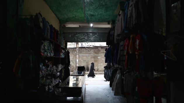 A Syrian woman walks past a workshop. (Abd Doumany/AFP)