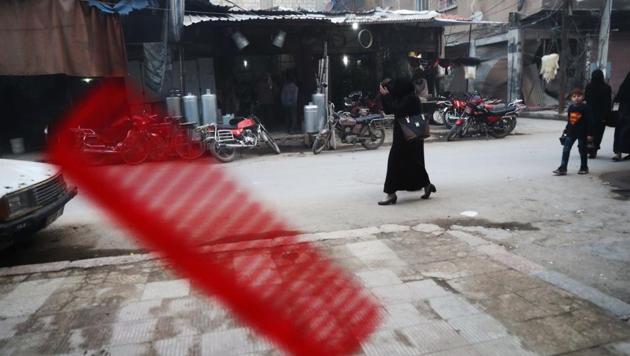 A picture taken from inside a barber's shop shows a Syrian woman walking in the rebel-held town of Douma, on the eastern outskirts of the capital Damascus. (Abd Doumany/AFP)
