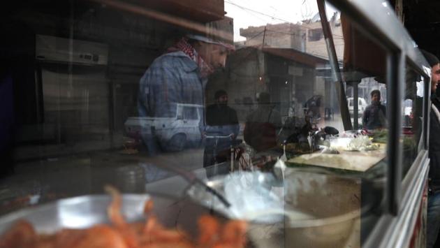 The reflection of Syrian men is seen as they shop for food. (Abd Doumany/AFP)