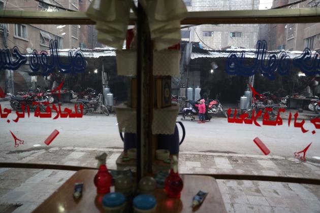 A Syrian woman and a child are seen through a barber's shop window. (Abd Doumany/AFP)
