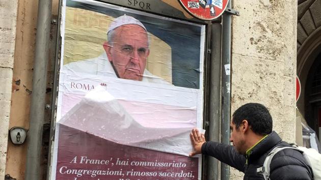A passerby lifts a paper sheet covering an anti-Pope Francis poster, in central Rome on Saturday.(AP photo) A passerby lifts a paper sheet covering an anti-Pope Francis poster, in central Rome on Saturday.(AP photo)