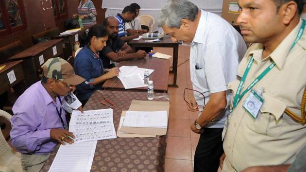 Defence minister Manohar Parrikar finding his name in the voter list at a polling booth in Goa on Saturday.(PTI)