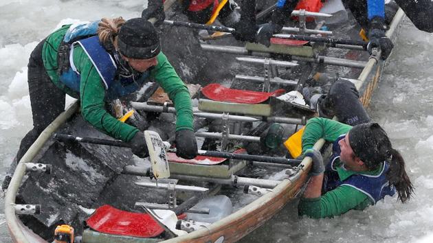 A member of Team Cuisina climbs back in the canoe after falling in the water during the ice canoe race at the Quebec Winter Carnival in Quebec City. (REUTERS)