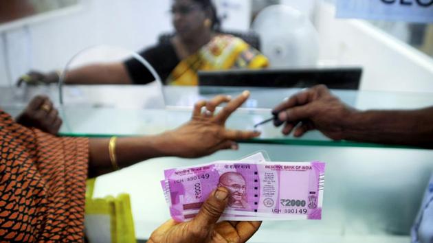 In this photograph taken on November 17, 2016, a woman holds Rs 2000 notes as she has her finger marked with indelible ink after exchanging 500 and 1000 rupee notes at a bank in Chennai.(AFP Photo)