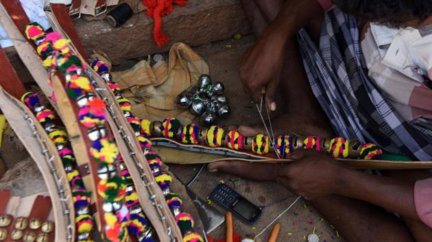 An artisan stitches a decorative necklace for a bull . (ARUN SANKAR / AFP)