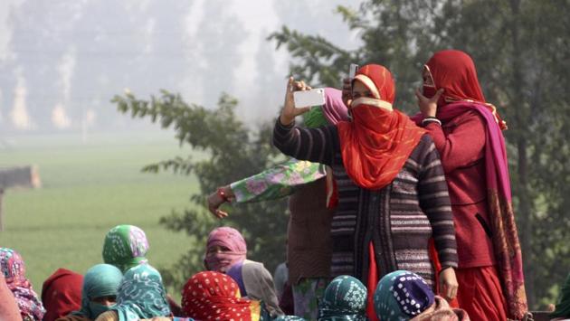 Protesters click photographs of security forces deployed along the protest site in Jassia village . (Manoj Dhaka / ht photo ) 