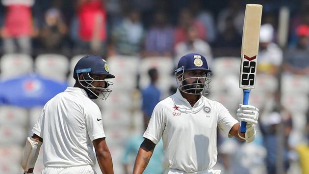 India's Cheteshwar Pujara, left, watches teammate Murali Vijay raise his bat after reaching his fifty. (AP)