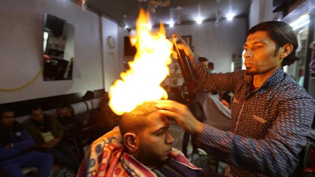 Palestinian barber Ramadan Odwan styles and straightens the hair of a customer with fire at his salon in Rafah, in the southern Gaza Strip. (braheem Abu Mustafa / REUTERS) Palestinian barber Ramadan Odwan styles and straightens the hair of a customer with fire at his salon in Rafah, in the southern Gaza Strip. (braheem Abu Mustafa / REUTERS)