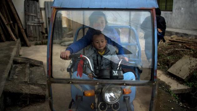 A woman rides on a tricycle with her son after ‘beat the Buddha’ celebrations in Yuxi village. (AFP Photo) A woman rides on a tricycle with her son after ‘beat the Buddha’ celebrations in Yuxi village. (AFP Photo)