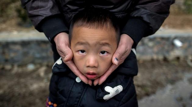 A man covers the ears of his son as firecrackers go off during the ‘beat the Buddha’ celebration in Yuxi village. (AFP Photo) A man covers the ears of his son as firecrackers go off during the ‘beat the Buddha’ celebration in Yuxi village. (AFP Photo)